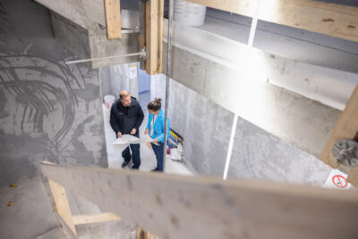 In einem Rohbau untrhlaten sich Gian Andri Lehner und Caty Emonet mit Blick auf einen Plan